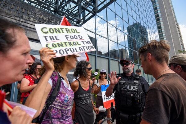 An officer from the Ottawa Police Service (OPS) talks to a protestor during a rally in support of Dutch farmers and Freedom Fighters Canada near the Embassy of the Kingdom of the Netherlands to Canada in Ottawa on July 23, 2022. (The Canadian Press/Spencer Colby)