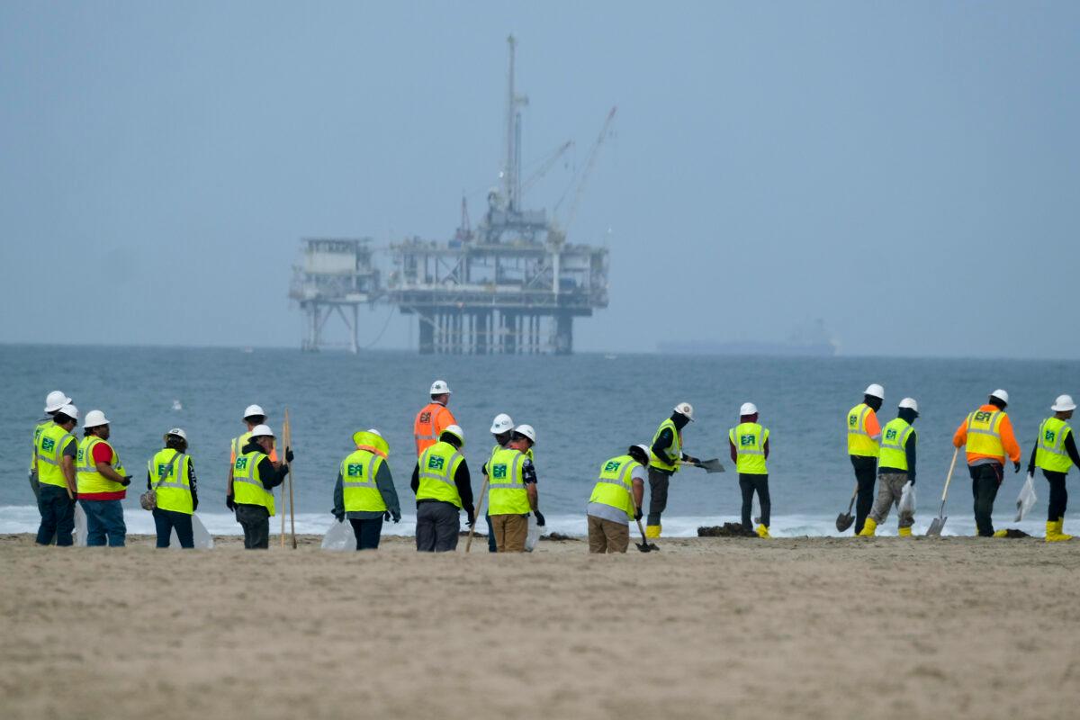 Workers in protective suits continue to clean the contaminated beach with a platform in the background in Huntington Beach, Calif., on Oct. 11, 2021. (Ringo H.W. Chiu/AP Photo)