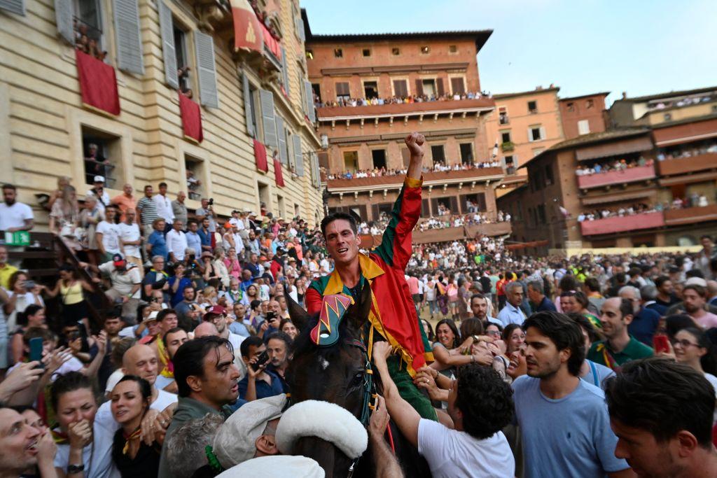 Italian jockey Giovanni Atzeni (C) riding Zio Frac for the Drago district, celebrates after winning the Palio di Siena on July 2, 2022, in Siena, Tuscany. (ALBERTO PIZZOLI/AFP via Getty Images)