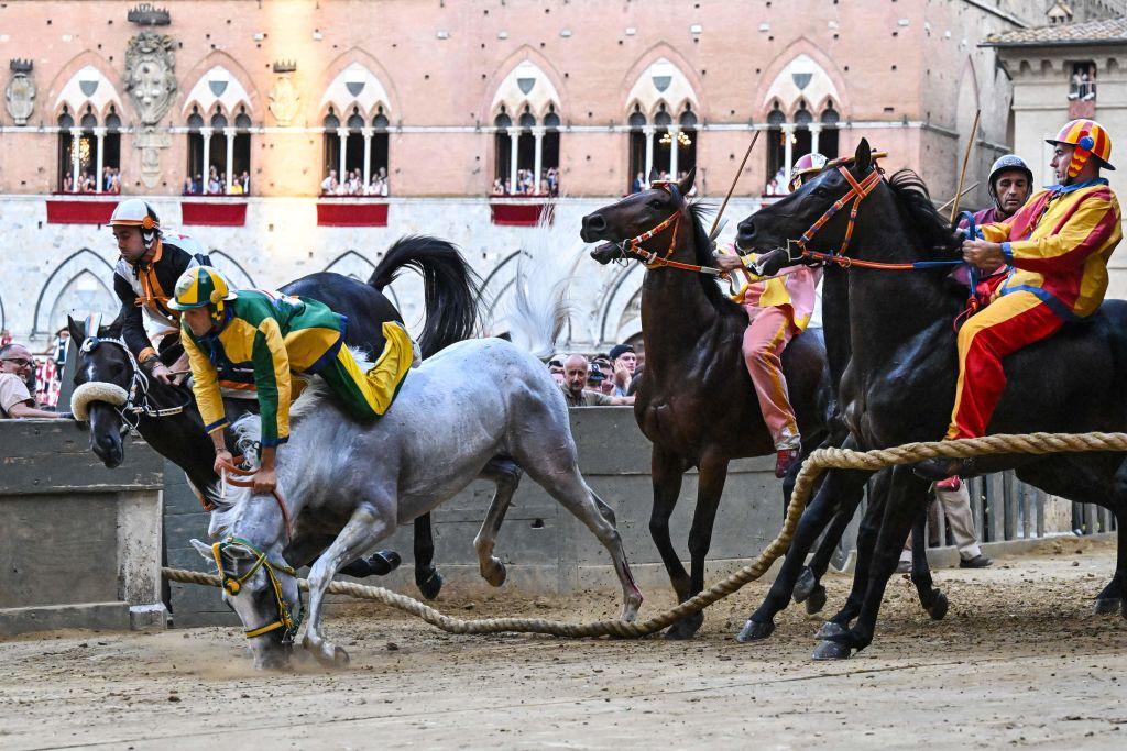 Italian jockey Stefano Piras (2nd L), who races for the "Bruco" district, falls during a false start of his horse, Uragano Rosso, during the historic Italian horse race Palio di Siena on July 2, 2022, in Siena, Tuscany. (ALBERTO PIZZOLI/AFP via Getty Images)