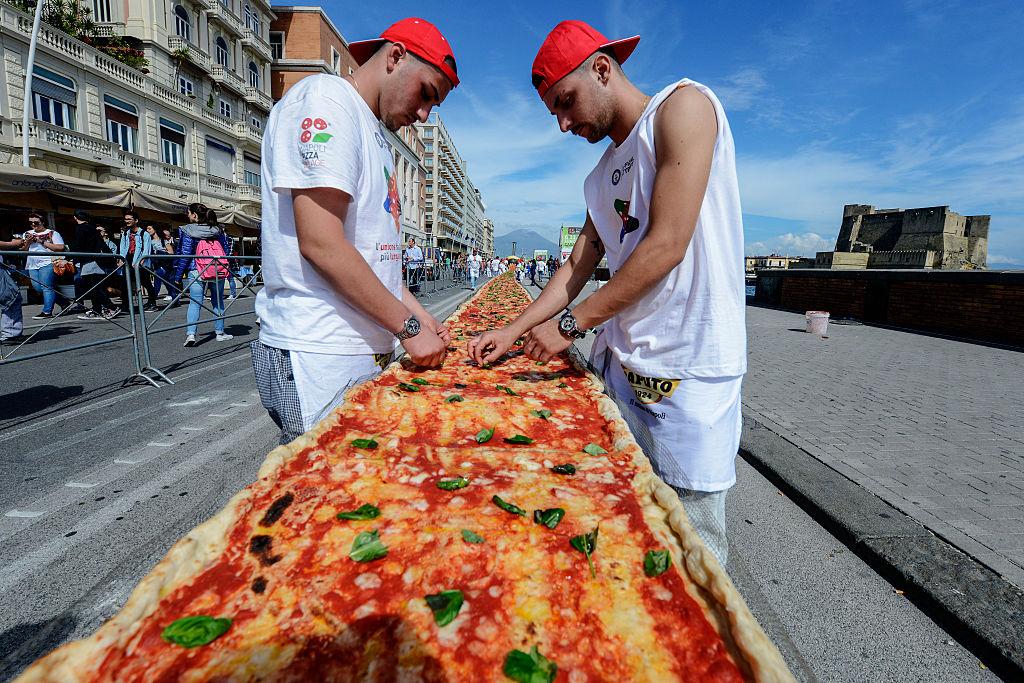 Neapolitan pizza-makers attempt to make the longest pizza to break a Guinness World Record along the seafront of Naples, Italy, on May 18, 2016. For the wood-fired pizza, which measured two kilometers (1.24 miles), they used 2,000 kg (4,409 pounds) of flour, 1,600 kg (3,527 pounds) of tomatoes, 2,000 kg (4,409 pounds) of mozzarella, 200 liters (528 gallons) of oil, and 30 kg (66 pounds) of fresh basil. (Mario Laporta/AFP via Getty Images)