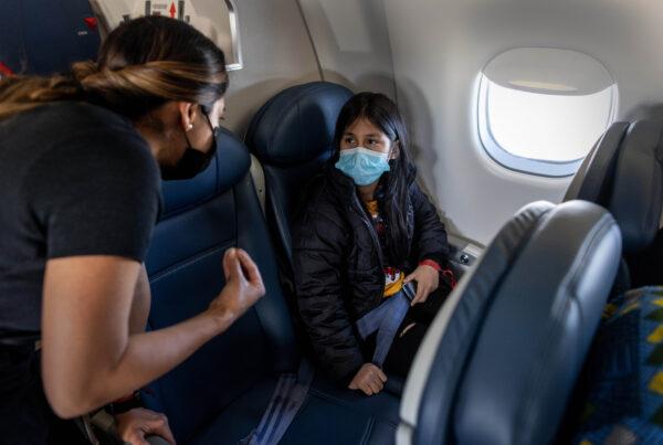 A 10-year-old unaccompanied alien minor from Honduras speaks with a flight attendant while flying to join her extended family in southern Indiana from near Louisville, Ky., on April 23, 2021. (John Moore/Getty Images)