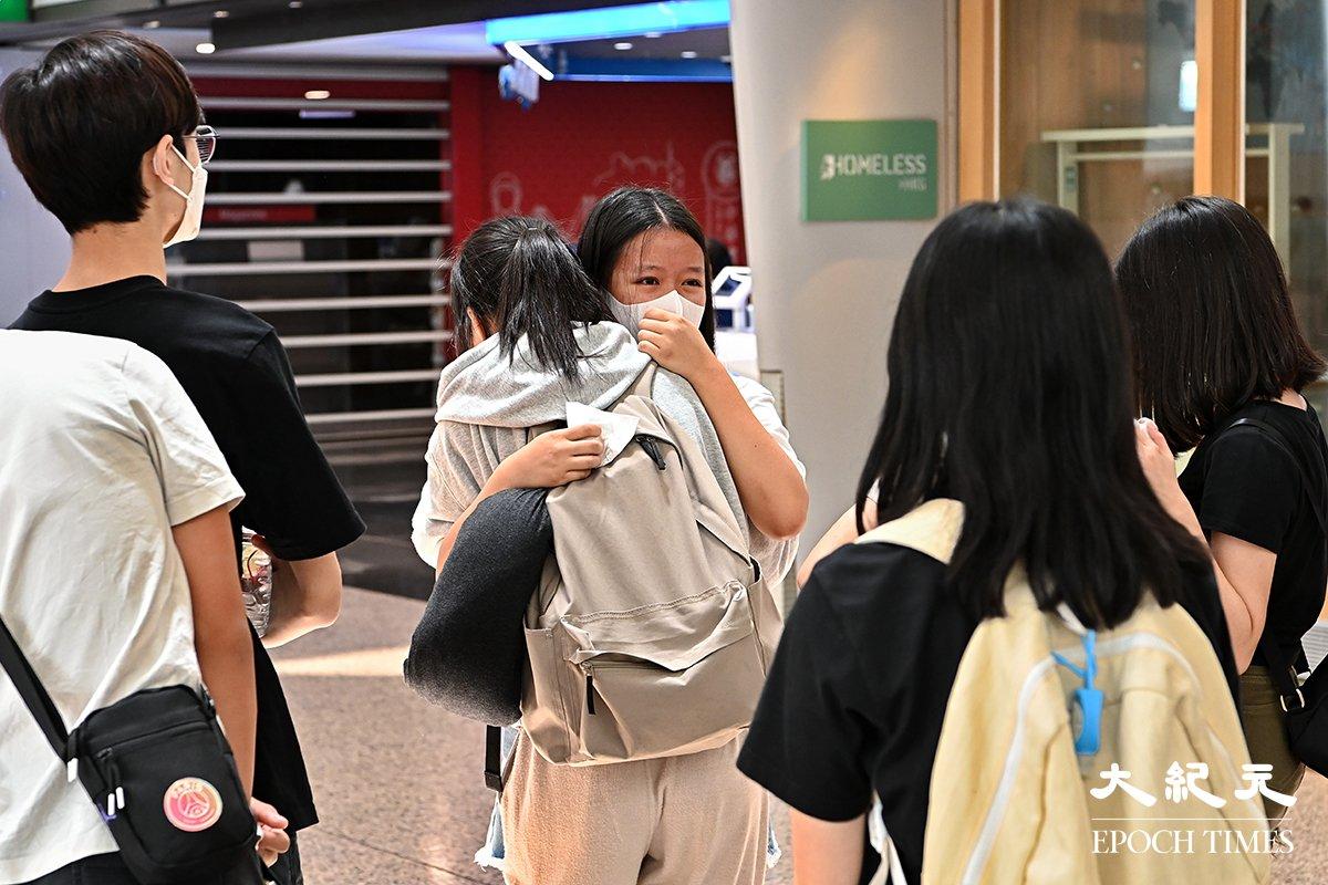 Travelers hug friends at the departure terminal of Hong Kong International Airport. (Terence Tang/The Epoch Times)