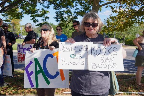 A woman with signs "Don't MAGA our schools" and "Kooks ban books" at a rally outside the Loudoun County Public Schools (LCPS) administration building in Ashburn, Va., on Sept. 13, 2022. (Terri Wu/The Epoch Times)