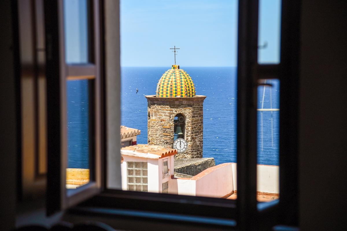 Church tower seen through a window with the sea in the background, in Sardinia, Italy. (AndreeaStoica/Shutterstock)
