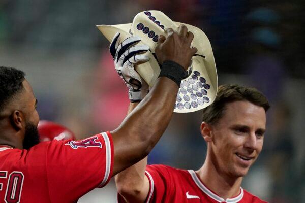 Los Angeles Angels' Luis Rengifo, left, hands Matt Duffy, right, a cowboy hat that has team stickers placed on it after Duffy hit a two-run home run in the second inning of a baseball game against the Texas Rangers in in Arlington, Texas, on Sept. 20, 2022. (Tony Gutierrez/AP Photo)