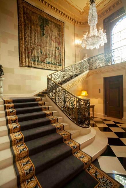 The main central stairway is a transition from private quarters to family activities. The intricate crystal chandelier is surrounded by an elegant wrought iron balustrade. A large tapestry is featured. (J.H.Smith/Cartiophotos)