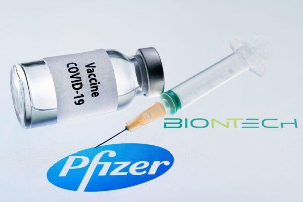 A bottle is shown reading "Vaccine COVID-19" and a syringe next to the Pfizer and Biontech logo on Nov. 23, 2020. (Joel Saget/AFP via Getty Images)