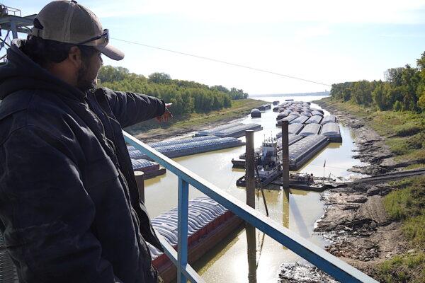 Poinsett Rice and Grain barge loader Raul Rivas points to the long line of barges awaiting delivery of soybeans on Oct. 20, 2022. (Allan Stein/The Epoch Times)