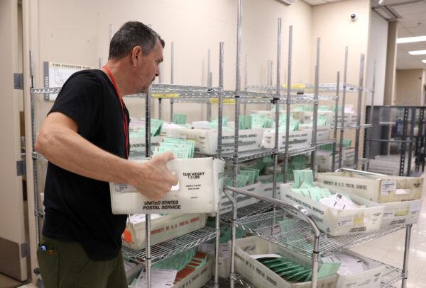 An election worker carries trays filled with mail-in ballots to open and verify at the Maricopa County Tabulation and Election Center in Phoenix, Ariz., on Nov. 11, 2022. (Justin Sullivan/Getty Images)