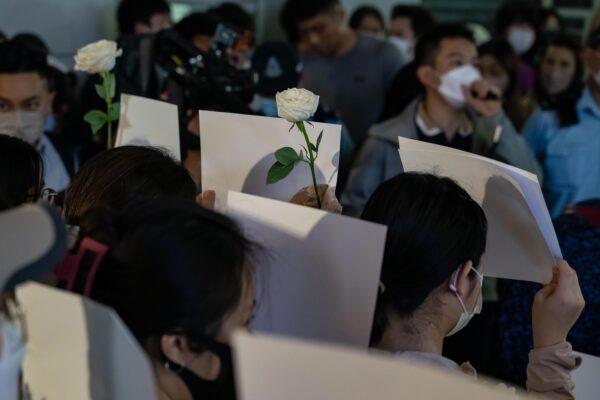 People hold sheets of blank paper in protest of COVID restrictions in mainland China as police set up a cordon during a vigil in the central district in Hong Kong on Nov. 28, 2022. (Anthony Kwan/Getty Images)