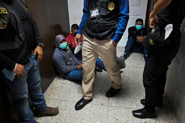 Police officers with alleged members of a human trafficking gang sit on the floor of a court after being arrested in Guatemala City on Oct. 24, 2022. (Johan Ordonez/AFP via Getty Images)
