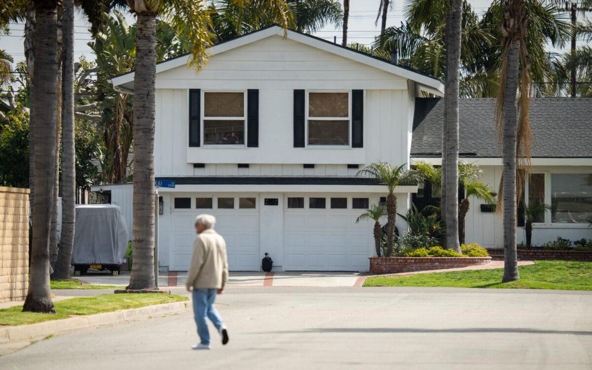 A resident walks by a house in Huntington Beach, Calif., on March 17, 2023. (John Fredricks/The Epoch Times)