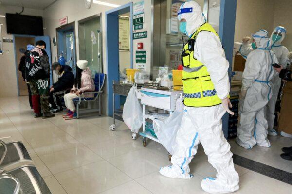 A security personnel in a protective suit keeps watch as medical workers attend to patients at the fever department of Tongji Hospital, a major facility for COVID-19 patients in Wuhan, Hubei Province, China, Jan. 1, 2023. (Staff/Reuters)