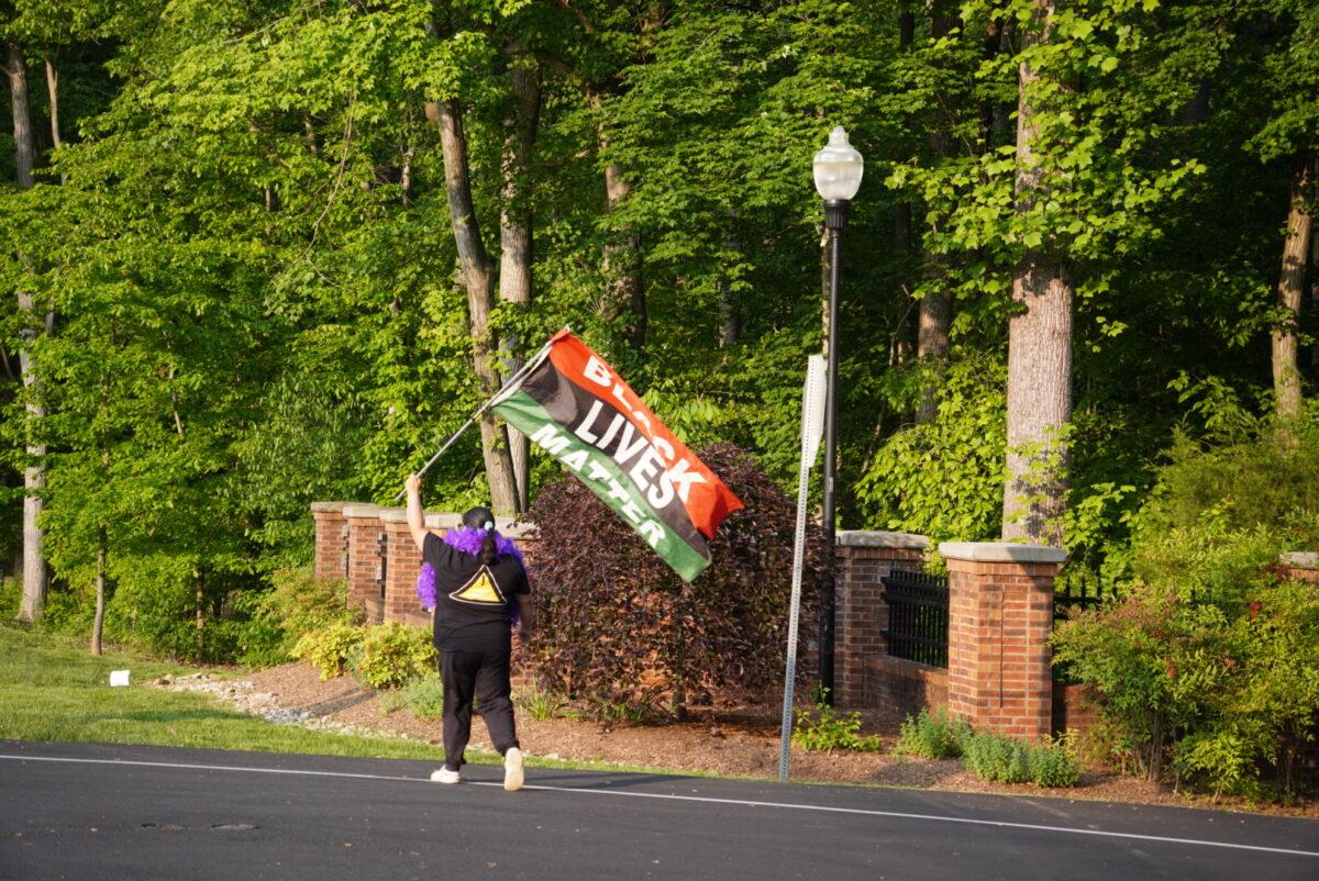 An abortion advocate flies a "Black Lives Matter" flag during a May 11, 2023, protest outside Justice Clarence Thomas's Virginia home. (Joseph Lord/The Epoch Times)