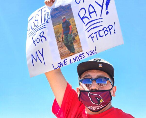 A nephew of Raymond Mattia holds a sign during a protest in Why, Ariz., on May 27, 2023. (Allan Stein/The Epoch Times)