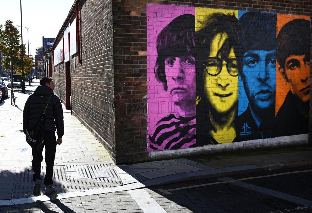 Pedestrians pass a mural depicting members of British rock band The Beatles (L-R) Ringo Starr, John Lennon, Paul McCartney and George Harrison on the side of a building in Liverpool, northwest England on Oct. 13, 2020. (Paul Ellis/AFP via Getty Images)