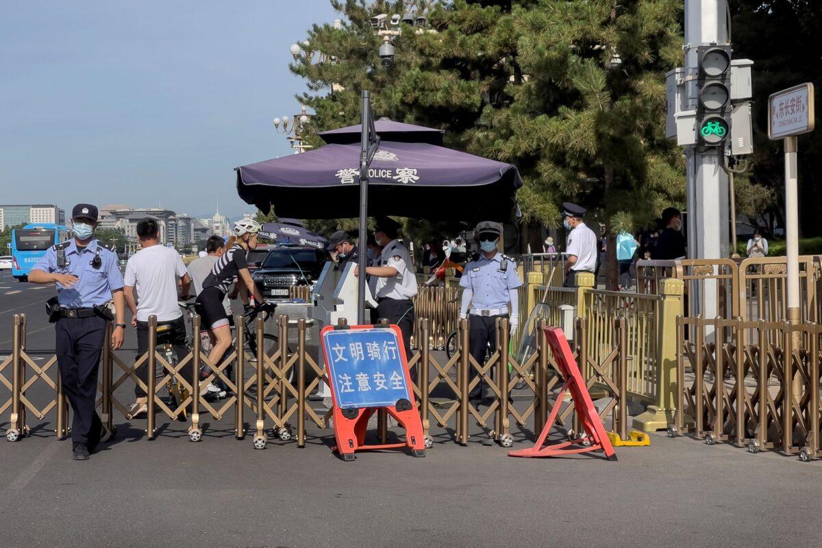 A police officer (L) gestures to a journalist to stop as people on bicycles are ordered to stop for identification check at a checkpoint along a street near Tiananmen Square in Beijing on June 4, 2023, during the 34th anniversary of the CCP’s bloody 1989 massacre of pro-democracy protesters. (Andy Wong/AP Photo)