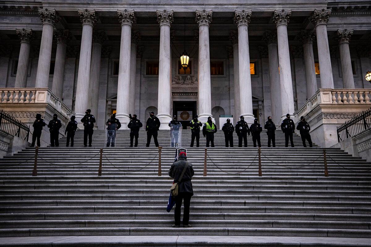 A lone supporter of President Trump stands on the steps to the U.S. Capitol below a line of police officers on Jan. 6, 2021. (Samuel Corum/Getty Images)