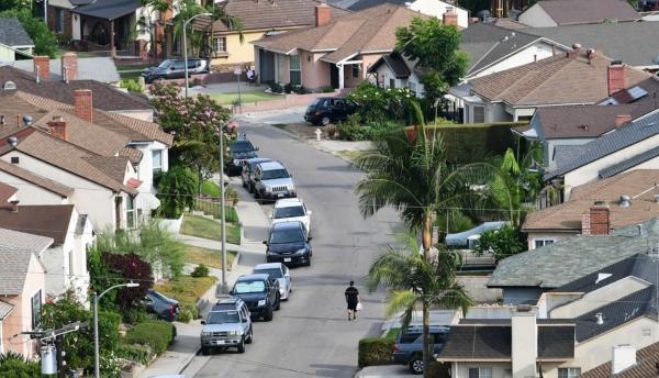 A man walks along a street in a neighborhood of single family homes in Los Angeles on July 30, 2021. (Frederic J. Brown/AFP via Getty Images)