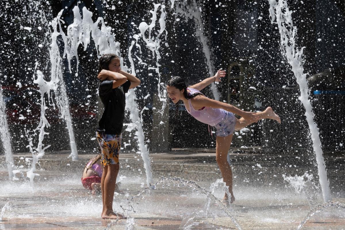Sisters Olivia, 10, and Evelyn Black, 12, play in the Gateway Fountain at Discovery Green park to escape the hot weather in Houston on July 18, 2023. (Adrees Latif/Reuters)