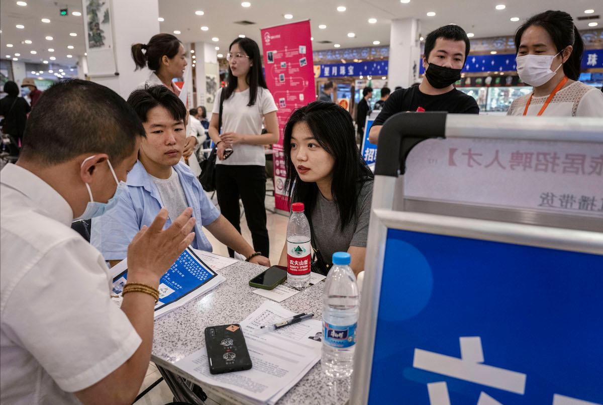 People talk to a recruiter at a job fair in Beijing on June 9, 2023. (Kevin Frayer/Getty Images)
