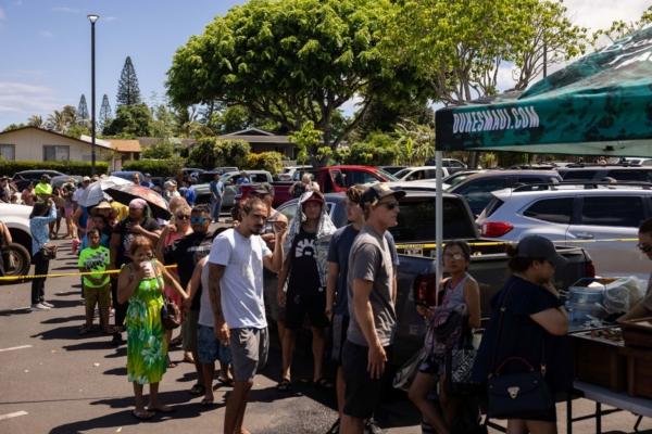 La gente espera en fila para recibir comidas gratis en un centro de distribución para los afectados por los incendios de Maui en Honokawai Beach Park en Napili-Honokowai, Hawaii, el 14 de agosto de 2023. (Yuki Iwamura/AFP vía Getty Images)