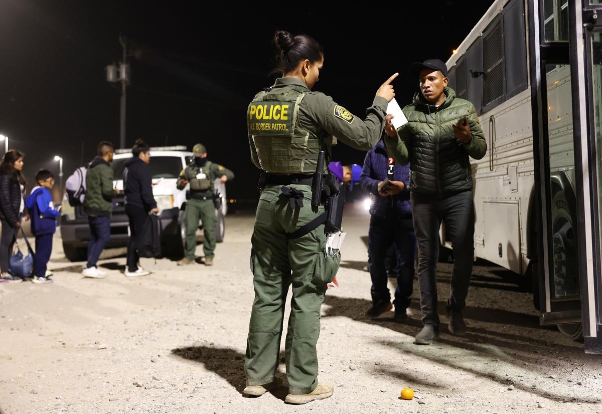 A Border Patrol agent gestures as illegal immigrants prepare to board a bus to a U.S. Border Patrol processing center after crossing into Arizona from Mexico in Yuma, Ariz., on May 11, 2023. (Mario Tama/Getty Images)