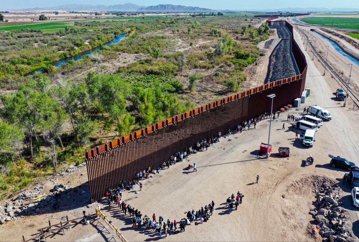 Illegal immigrants wait in line to be processed by the U.S. Border Patrol after crossing through a gap in the U.S.–Mexico border barrier in Yuma, Ariz., on May 21, 2022. (Mario Tama/Getty Images)