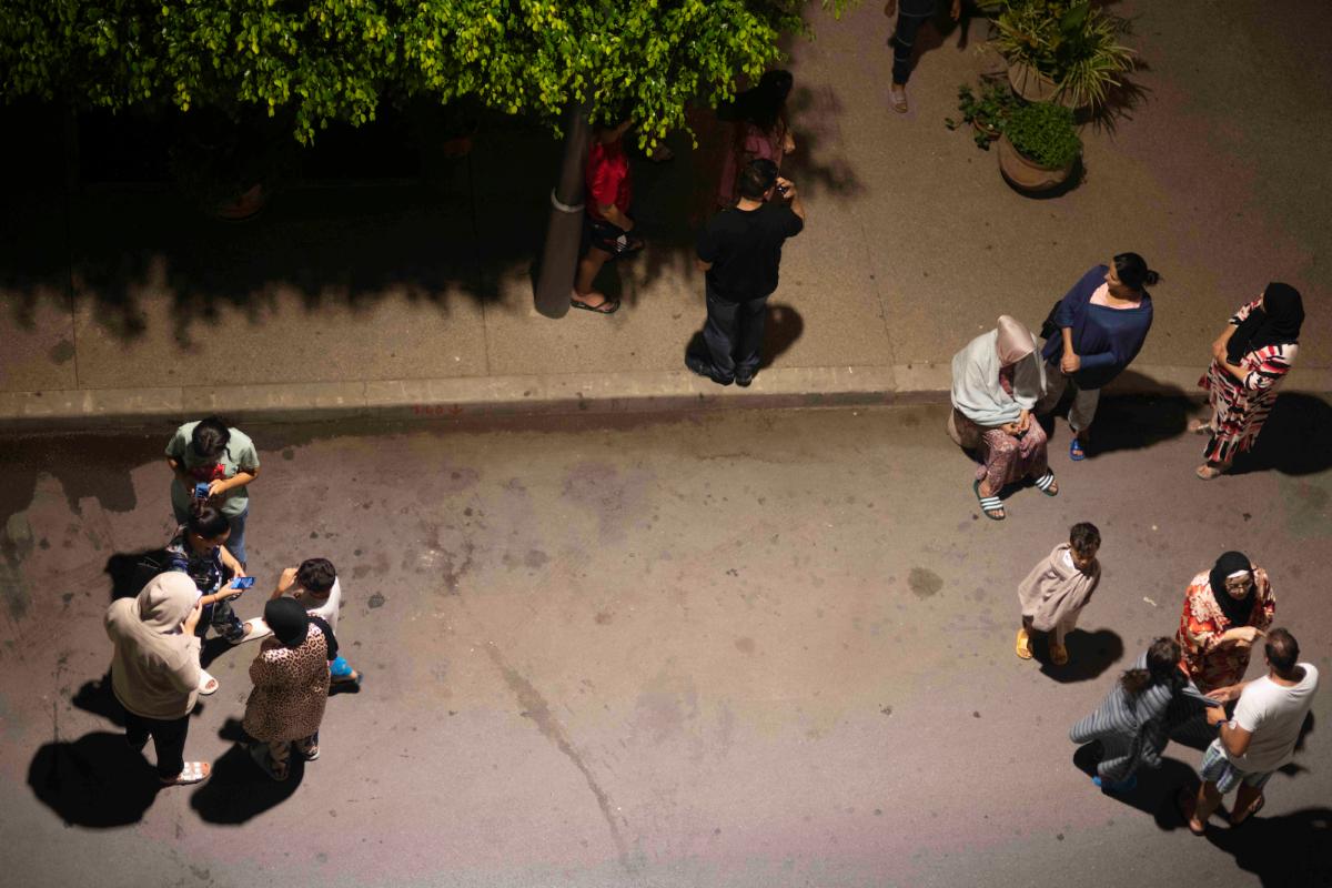 People take shelter and check for news on their mobile phones after an earthquake in Rabat, Morocco, on Sept. 8, 2023. (Mosa'ab Elshamy/AP Photo)