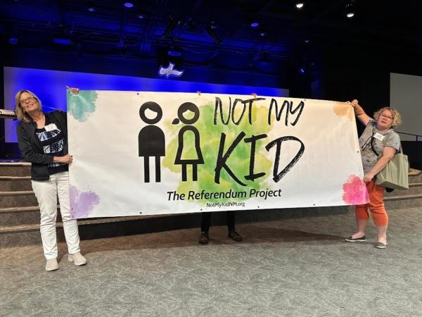 Jenny Culver (left) and Ramona Goolsby (right) hold a banner promoting the Referendum Project's "Not My Kid" video campaign. (Courtesy of Carla Sonntag)