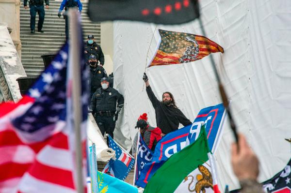 A man waves a flag from the stairs of the U.S. Capitol Building after breaking a police line as protesters and supporters of U.S. President Donald Trump gather outside the building on Jan. 6, 2021. (Joseph Prezioso/AFP via Getty Images)