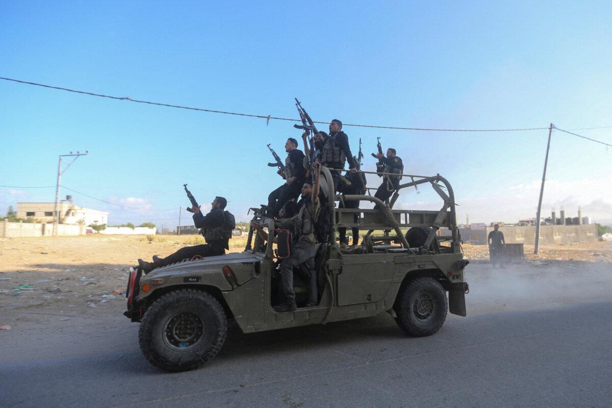 Palestinian gunmen ride an Israeli military vehicle that was seized in infiltrated areas of southern Israel, in the northern Gaza Strip, on Oct. 7, 2023. (Ahmed Zakot/Reuters)