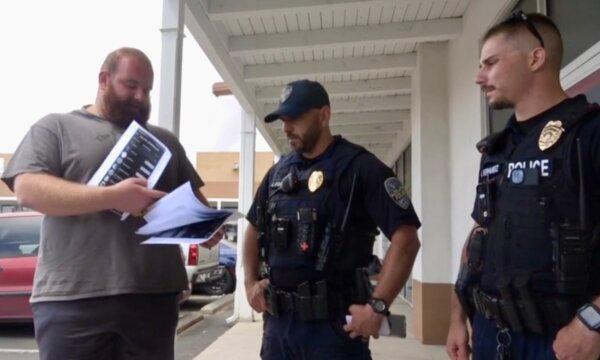 Alex Rosen (L), founder of Predator Poachers, shows evidence to police after confronting a child pornography trader. (Rumble/Screenshot via The Epoch Times)