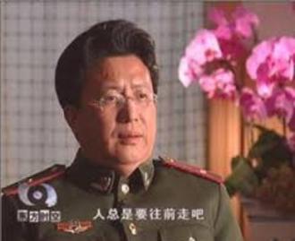 Dr. Shen Zhongyang is interviewed on Chinese television in his paramilitary uniform. The subtitle says "humankind will always make progress."