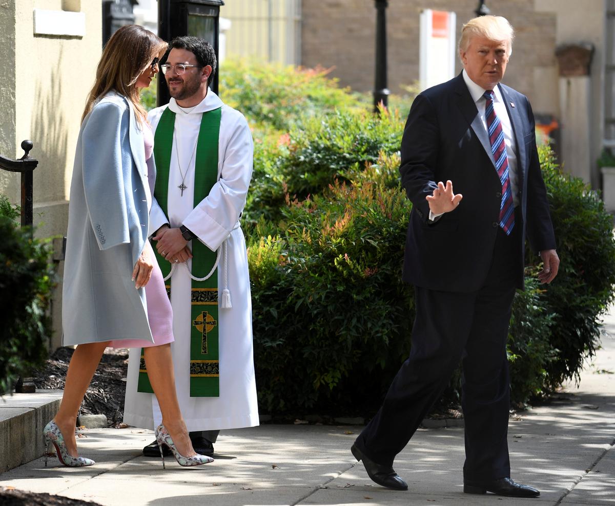 President Donald Trump waves to the press, as he departs St. John's Episcopal Church and Assistant Rector D. Andrew Olivo, (C), with First Lady Melania Trump after they attended services for a national "Day of Prayer", for victims of the Hurricane Harvey flooding in Texas, in Washington on Sept. 3, 2017. (REUTERS/Mike Theiler)
