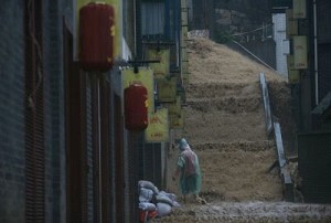 A restaurant worker piles sand bags in an effort to keep flood waters from Nanbin Road July 18, 2007 in Chongqing Municipality, China. (China Photos/Getty Images)