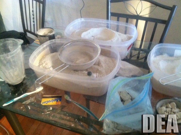Heroin seen in containers with a foundation of a grinder, a sifter, and other drug selling tools. (DEA)