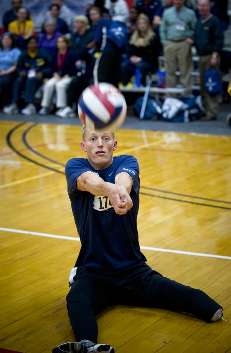 U.S. Navy Parachute Rigger 3rd Class Michael Johnston bump passes the ball to a teammate during a sitting volleyball game against Army.  (Photo by MC1 R. Jason Brunson)
