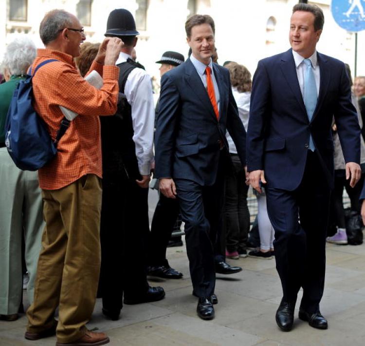 A member of the public (L) takes a photograph of Britain's Conservative Prime Minister, David Cameron (R), and Liberal Democrat Deputy Prime Minister, Nick Clegg (2nd L), as they walk to the Houses of Parliament to attend the State Opening of Parliament.  (Ben Stansall/AFP/Getty Image)