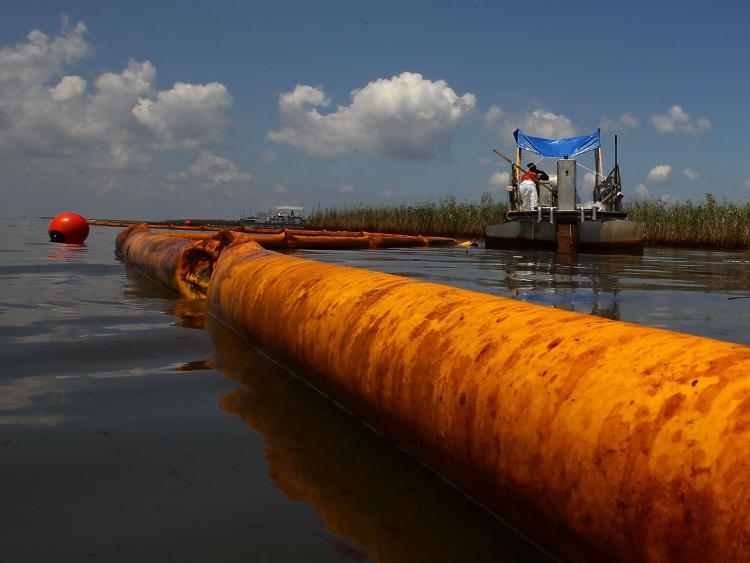An oil containment boom floats in the water as contract workers from BP use skimmers to clean oil from a marsh near Pass a Loutre in Louisiana. (Win McNamee/Getty Images)