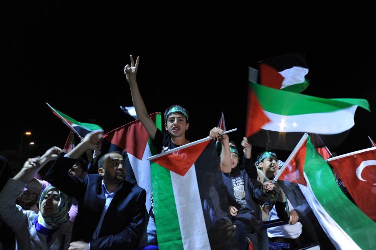 Demonstrators chant slogans and waves Palestinian flags at airport as they welcome Turkish activists expelled from Israel. (Mustafa Ozer/AFP/Getty Images)