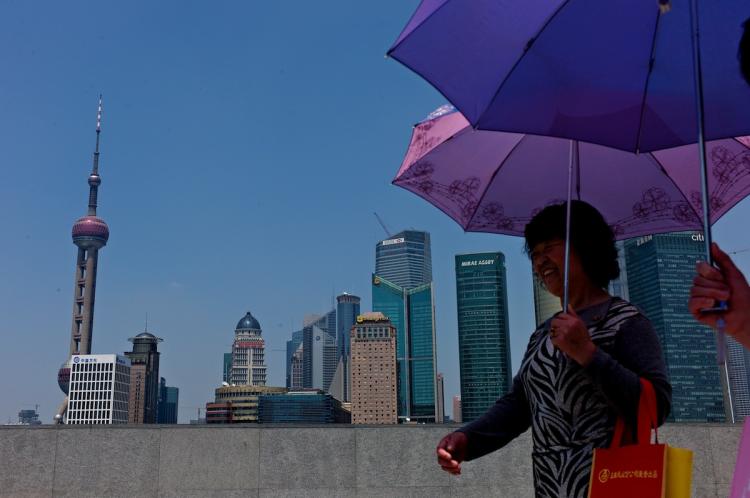 BUSINESS CENTER: Two women walk past the skyline of Shanghai's central business district. China is keen on developing its own global investment bank to rival competitors in Europe and the United States.