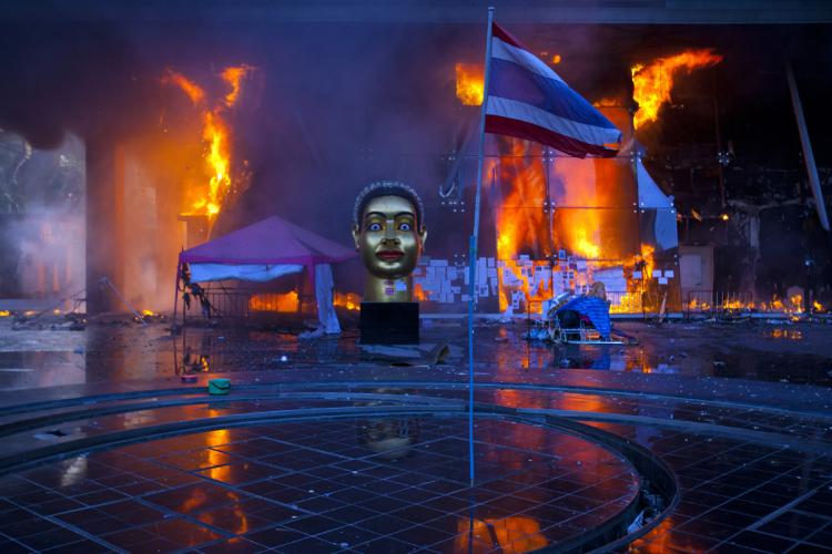 A Thai national flag is seen inside the devastated red shirt camp as a fire burns at the Central World Shopping Mall on May 19, 2010 in Bangkok. (Athit Perawongmetha/Getty Images)