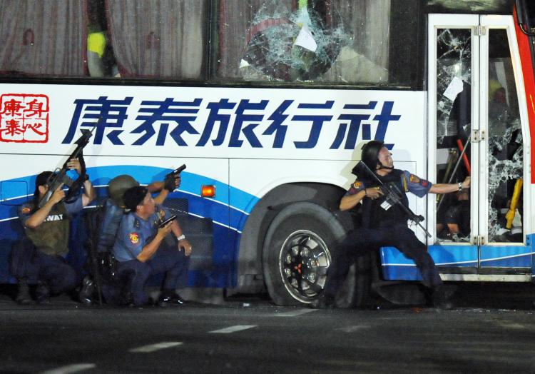 Philippine policemen take position as they start their attack on the tourist bus hijacked in Manila on August 23, 2010. (Ted Aljibe/AFP/Getty Images)