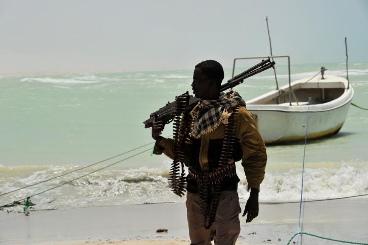 A Somali pirate carries his high-caliber weapon on a beach in the central Somali town of Hobyo on August 20, 2010. (Roberto Schmidt/AFP/Getty Images)