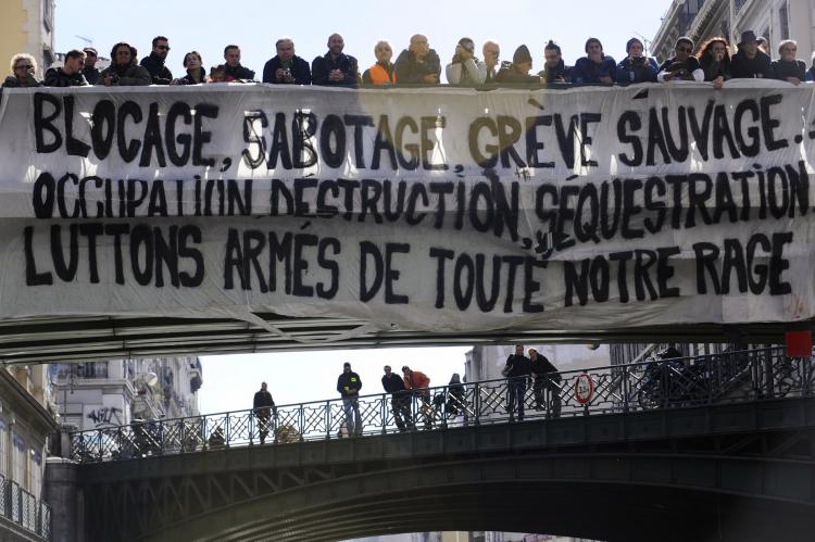 People stand behind a giant banner hanging on a bridge on Oct. 19 in Marseille, during a demonstration against the governmental pension reform. (Anne-Christine Poujoulat/AFP/Getty Images)