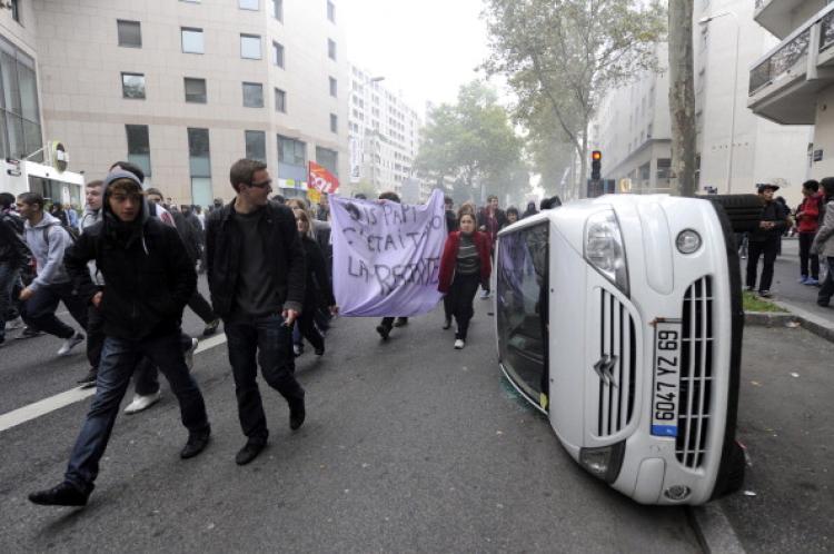 High school students walk past a damaged car as they demonstrate against France's government pensions reform on October 19,in Lyon. The latest mass protests against pensions reform in France drew 480,000 demonstrators into the streets by midday Monday.  (Philippe Desmazes/Getty Images )