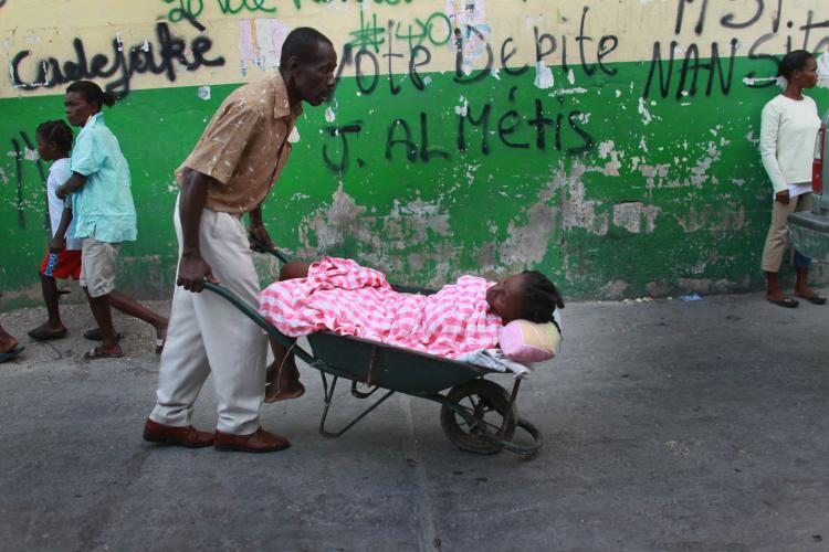 LOOKING FOR RELIEF: A man carries a sick woman to a field hospital of an international aid organization. An estimated 12,000 non governmental organizations are still currently present in Haiti. (Joe Raedle/Getty Images)