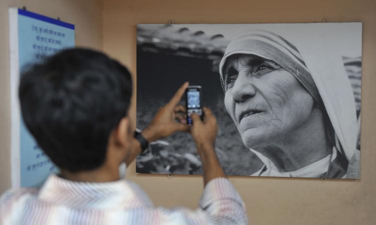 A boy takes a picture of an image of Mother Teresa that hangs in a carriage of the 'Mother Express' train in Mumbai. Research has found that witnessing extraordinary acts of compassion inspire others to do good in their own lives. (Sajjad Hussain/AFP/Getty Images)